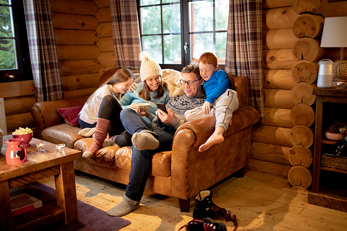 En familie som sitter og smiler i en sofa og ser på en mobil sammen